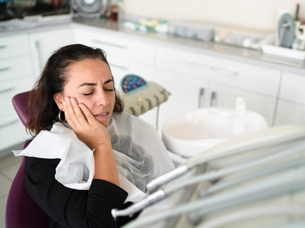 woman holding her cheek in pain 