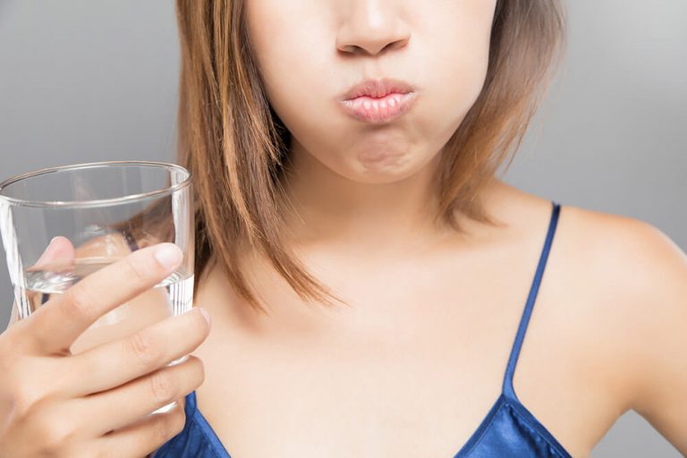 Closeup of a woman using homemade mouthwash to get rid of gingivitis