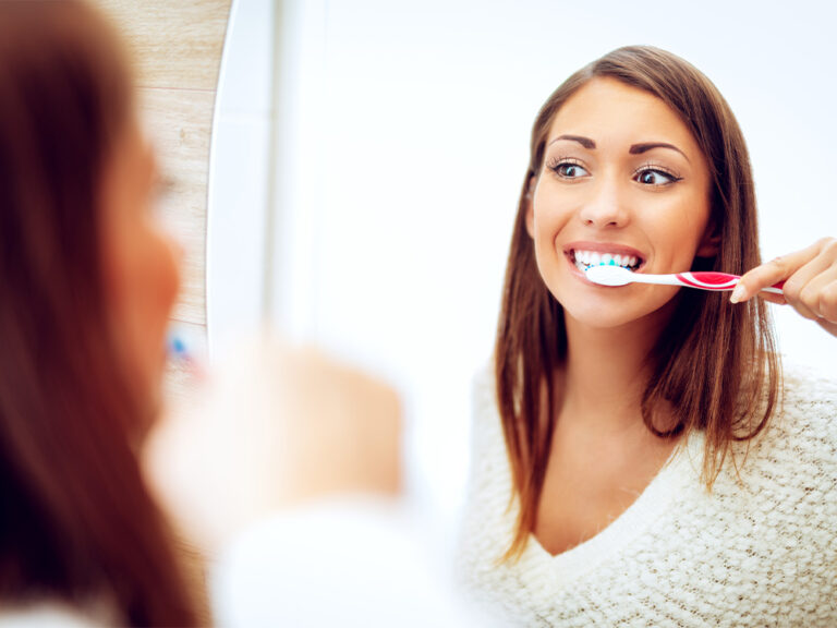 girl brushing teeth in mirror