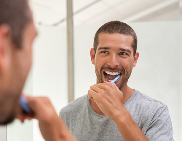 man brushing his teeth in the mirror